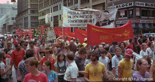 a wide shot of the marching protestors, many from the communist party, and others of varying subjects including an anti-draft sign