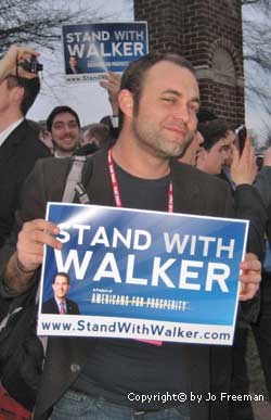 a crowd holds stand with walker signs