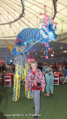 a women draped in an american flag scarf stands beneath a dragon