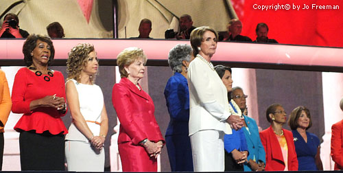 Minority Leader (and former Speaker) Nancy Pelosi stands in  front of the House women.
