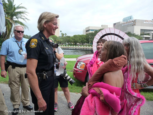 Code Pink women speak with a smiling policewoman