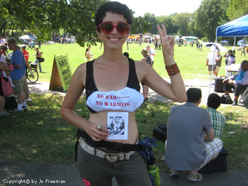 a smiling woman shoing the peace sign and wears a sportsbra with the sign no war no warming