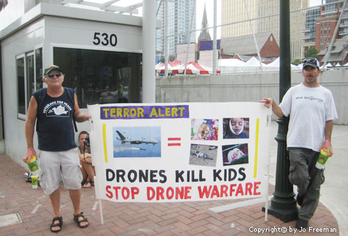 two men hold a sign reading Drones kill kids Stop drone warfare