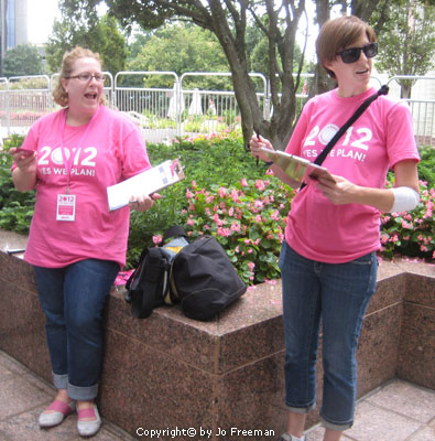 Two women in pink hold clipboards