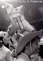 A female deligate wears a hat with a donkey pinata strapped to the top