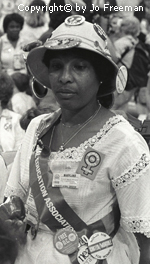 An African American female deligate wears many ERA related buttons and a National Education Association sash