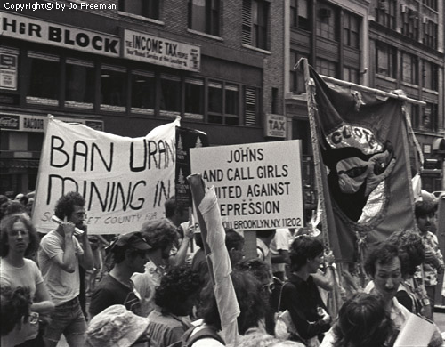 a dense crowd of protestors carry various signs, one about uranium mining