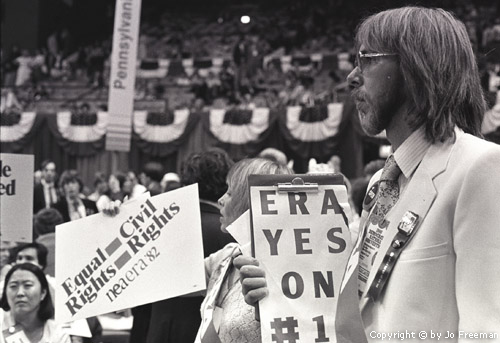 a man holds a sign reading ERA yes on #1, while in the background is another sign reading Equal Rights Equals Civil Rights