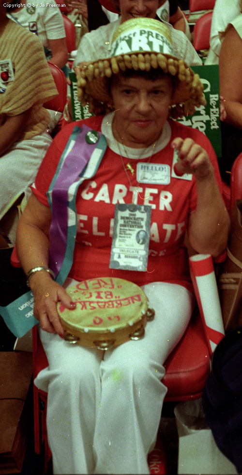 a female deligate wears a sombrero-like hat reading Carter.  From the edges of the hat hang many many peanut shells like fringe.