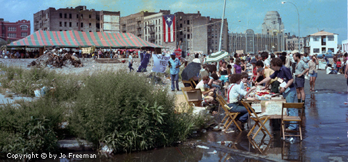 Many people gather in a decorated empty urban lot.