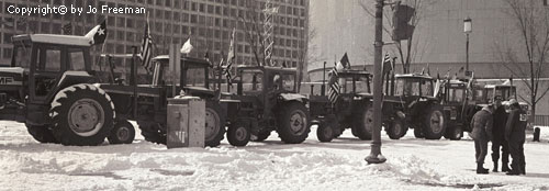 A line of tractors with flags in a snow covered open space on the Mall