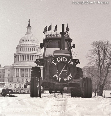 A tractor with a sign reading I did It My Way and many flags is parked in front of the capitol building
