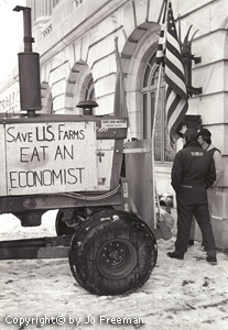 Farmers stand near an opulent building and a tractor with a sign reading Save US Farms, Eat an Economist
