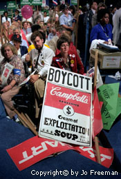 a woman holds a sign reading boycott Campbells cream of exploitation soup