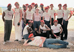 a group of young men and one woman stand for a photo, all wearing white shirts and red berets