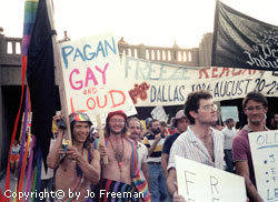 a group of young men carry colorful banners supporting gay rights, one reads pagan gay and loud