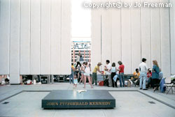 protestors stand at the JFK memorial.