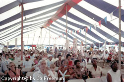 a large diverse audience gathered under a huge red white and blue tent